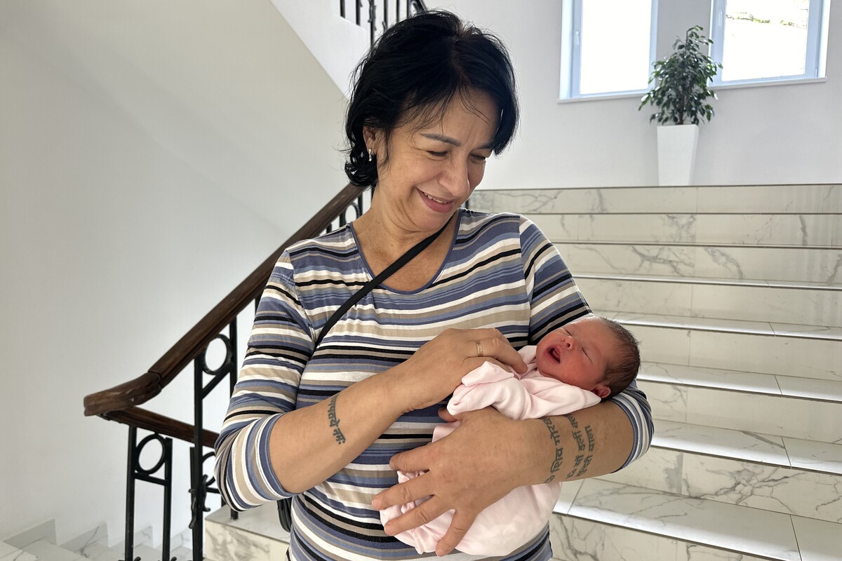 Наталя тримає дитину на руках і ніжно дивиться не неї