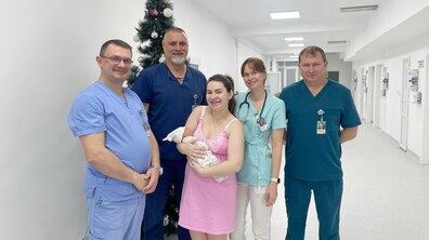 У холі лікарні львів'янка Юлія тримає сина Матвійка на руках, біля неї стоять лікарі; позаду новорічна ялинка